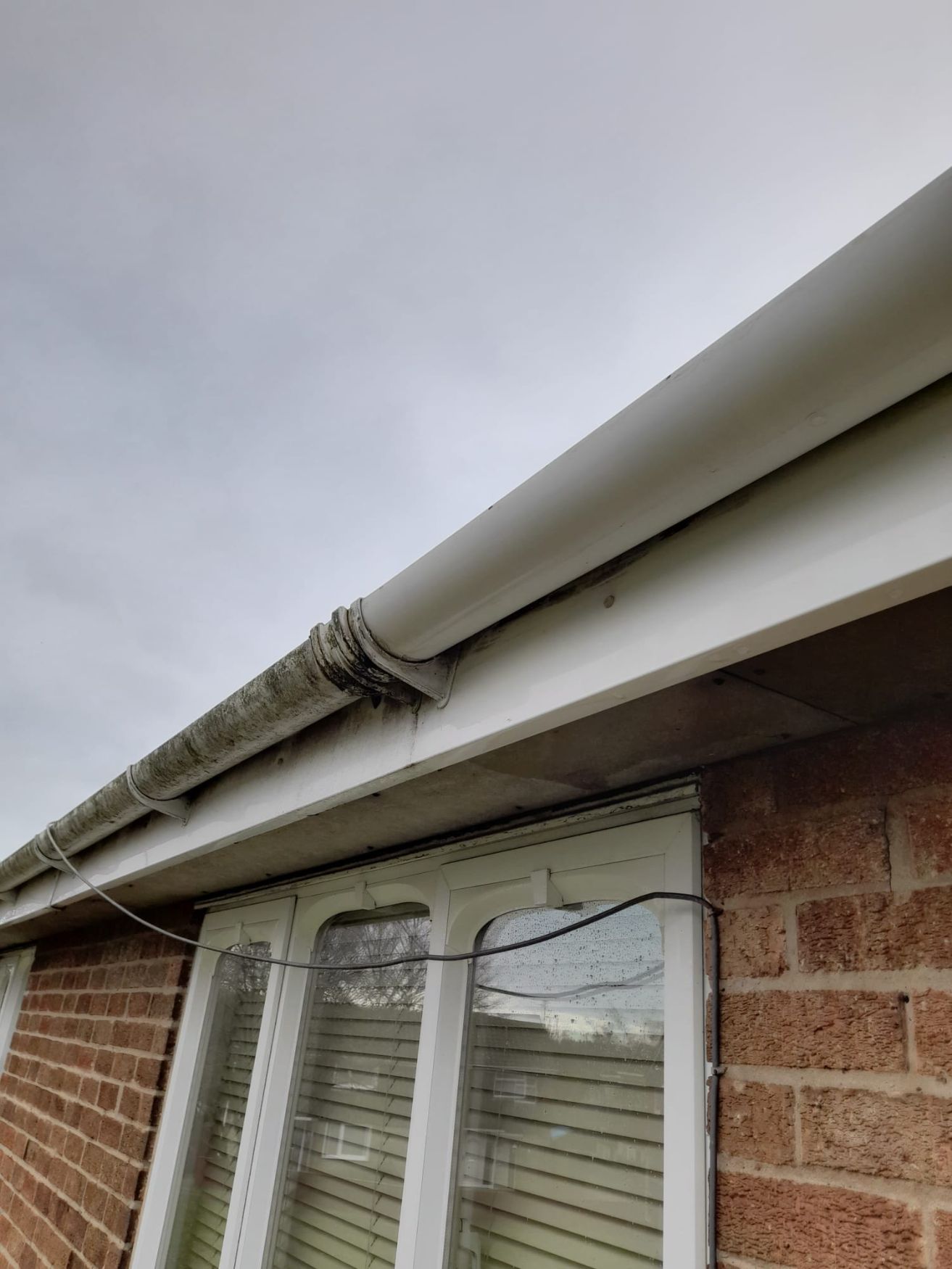 Gutter Cleaning Corby. Photo showing half washed gutters, one clean side, one dirty side